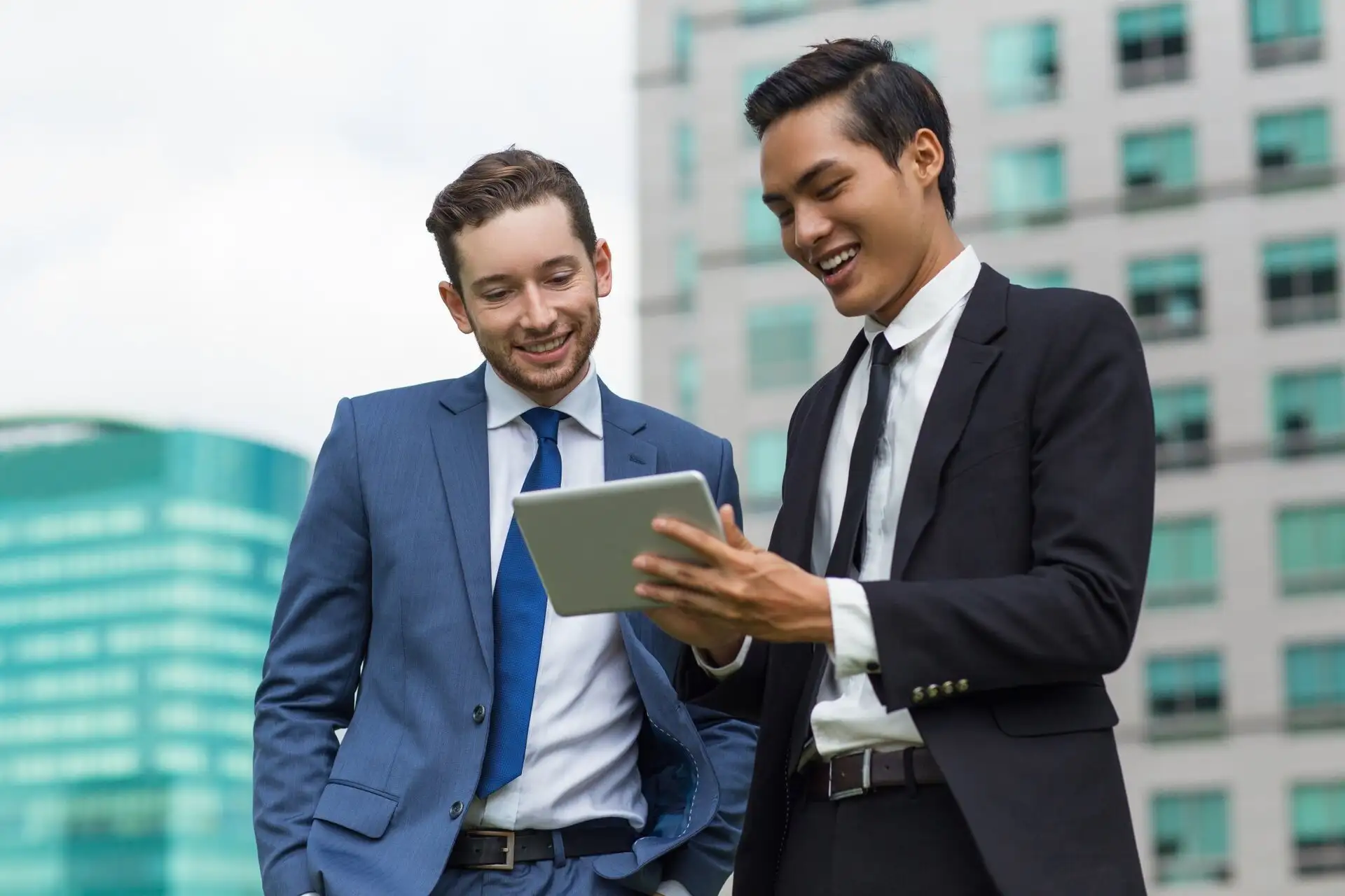 Two colleagues reviewing a digital dashboard on a tablet outside an office building