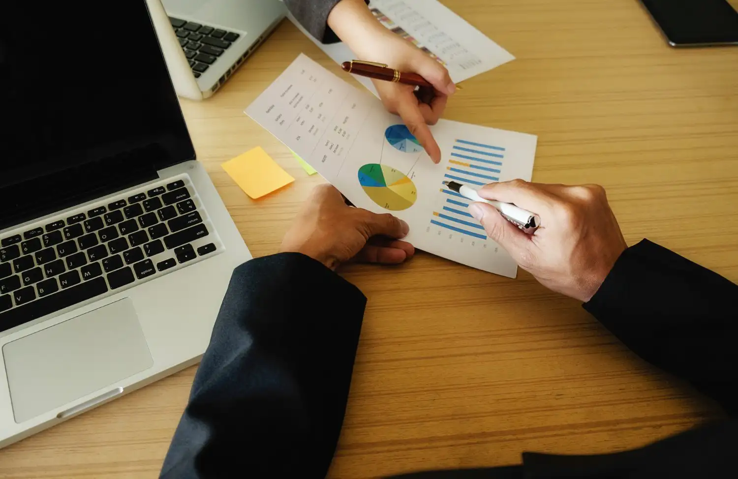 Analysts reviewing printed performance charts alongside a laptop